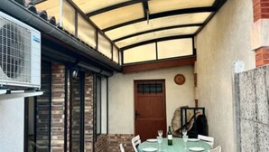 An outdoor patio with a covered seating area, a table set for dining, and a brick wall. - Vacation home in Andernos-les-Bains - Sleeps 6 - Near beach and market (Andernos-les-Bains)
