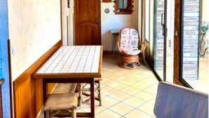 A room with a wooden ceiling, a tiled floor, a wooden table with chairs, a door, and a window with blinds. - Vacation home in Andernos-les-Bains - Sleeps 6 - Near beach and market (Andernos-les-Bains)