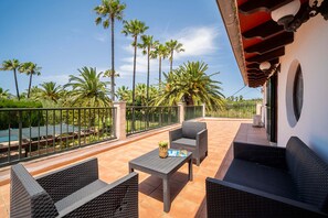 An outdoor patio with wicker furniture, a pool, and palm trees. - Can Tirenet accommodate 8 people Wi-Fi, swimming pool, tennis/padel (Alcudia)