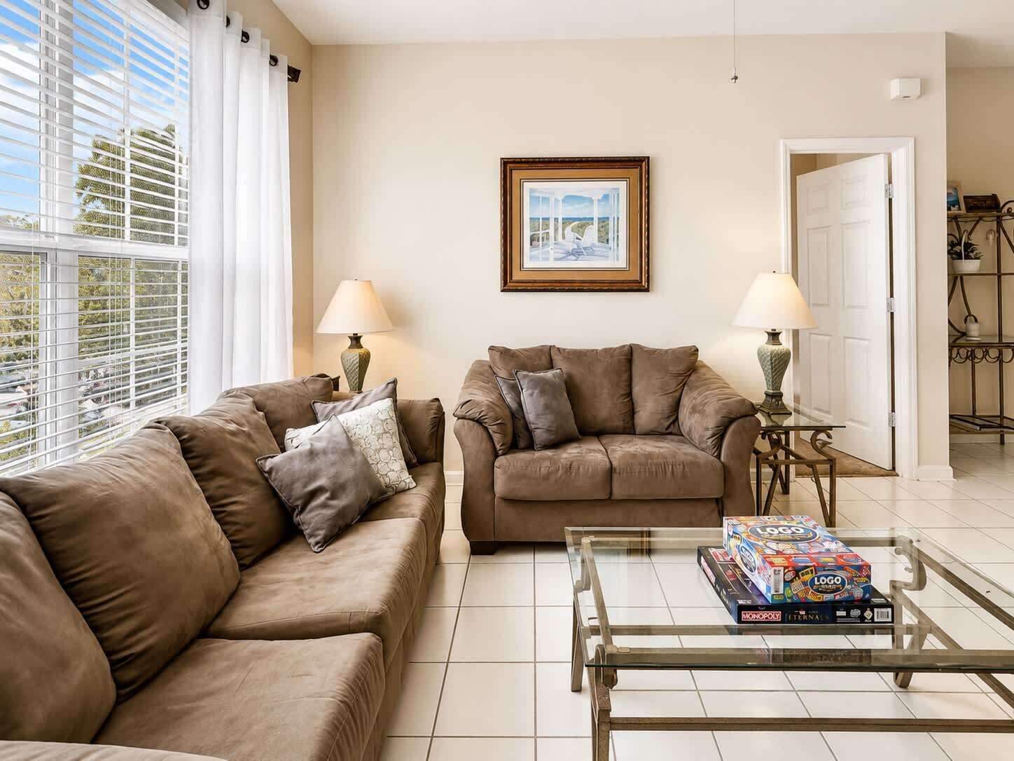 A living room with two sofas, a glass coffee table, and a framed picture on the wall.