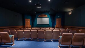 A theater with rows of seats, a large screen, and wooden paneling. - Universal Palms Retreat at Windsor Palms (Kissimmee)