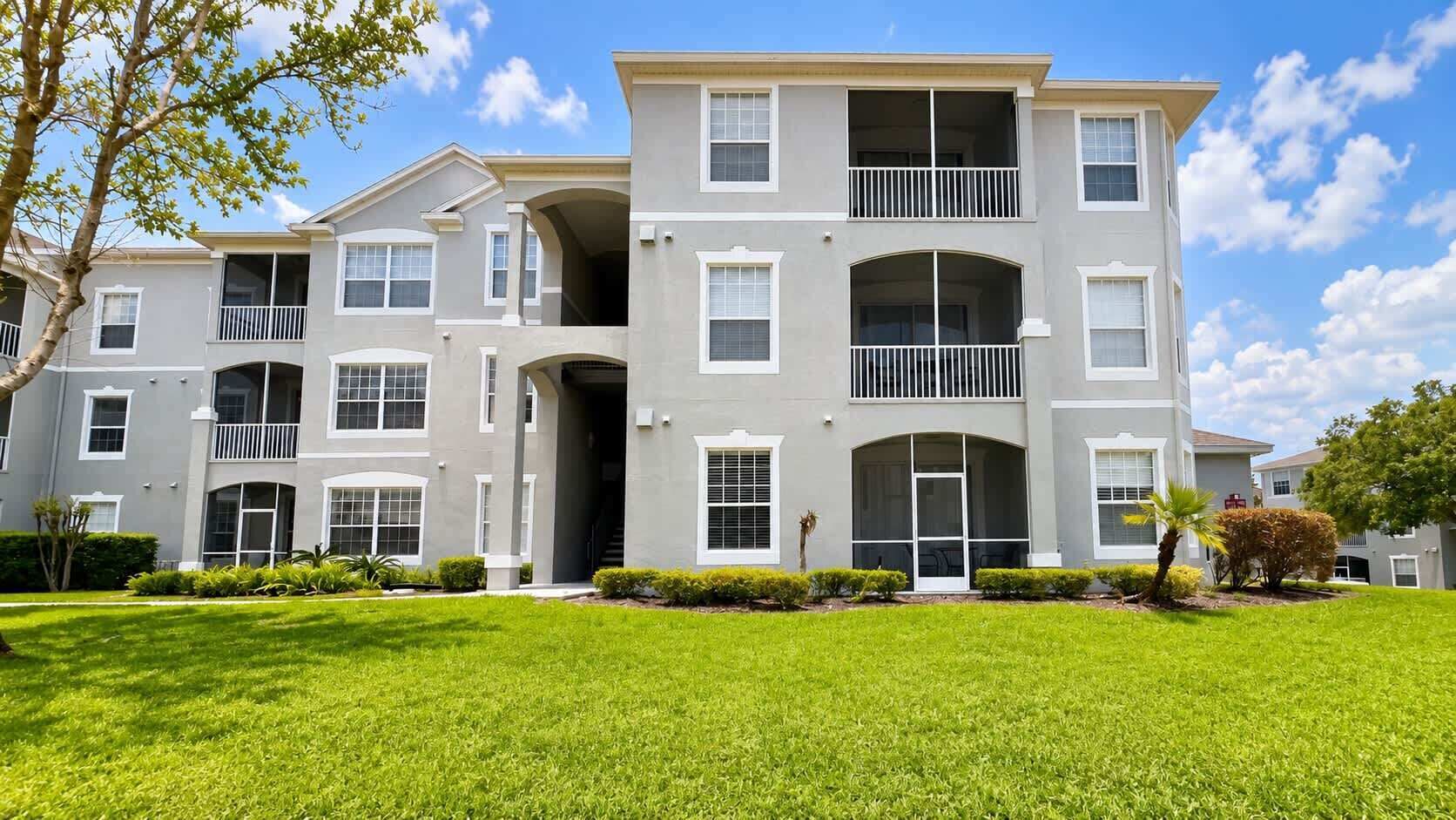 A multi-story residential building with a symmetrical facade, large windows, and a well-maintained lawn.