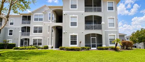 A multi-story residential building with a symmetrical facade, large windows, and a well-maintained lawn.