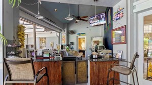 A bar area with a counter, chairs, and a television screen. - Universal Palms Retreat at Windsor Palms (Kissimmee)