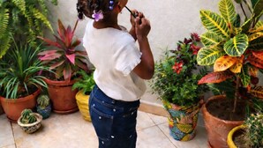 A child in a white shirt and blue jeans, surrounded by potted plants and a hanging basket with colorful items. - Azure Flat Casa Carlotta -100 mt from the Beach, Cozy and Authentic (Vila do Maio)