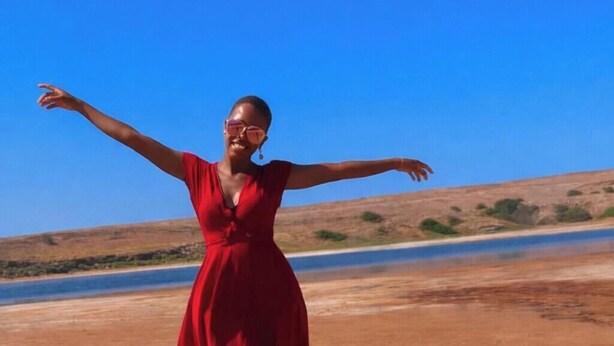 A person in a red dress standing on a dirt path with a clear blue sky and a body of water in the background. - Azure Flat Casa Carlotta -100 mt from the Beach, Cozy and Authentic (Vila do Maio)