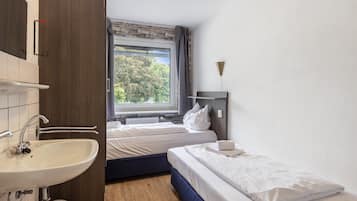 A bedroom with a window, a sink, and a bedside table.