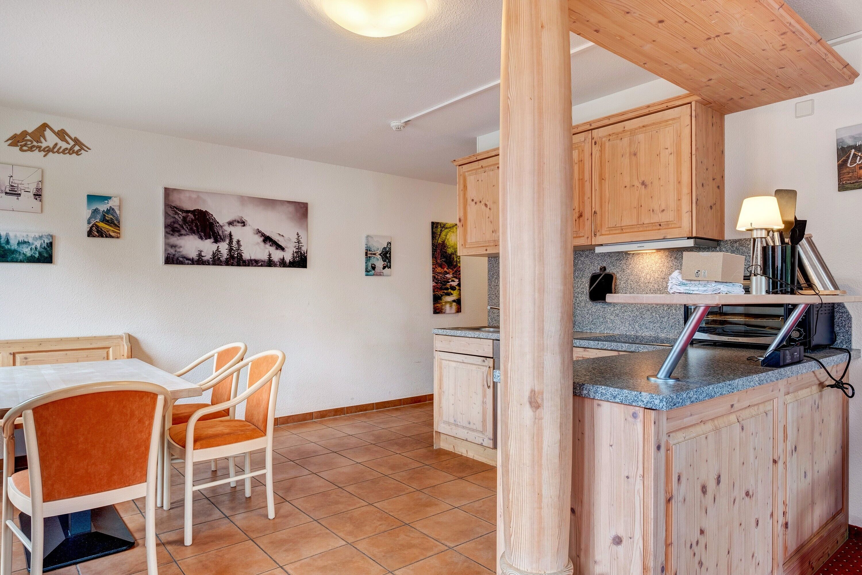 Una cocina con armarios de madera, una encimera y un comedor con sillas.