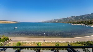 Eine Küstenansicht mit blauem Himmel, Sandstrand und ruhiger See.