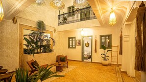 Ein großzügiger Innenraum mit hoher Decke, ein Balkon mit schmiedeeisernem Geländer und verschiedenen Pflanzen.