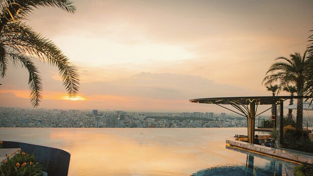 A pool with a city view, palm trees, and a sunset. - Terra Royal - Luxury Apartment & Hotel in Ho Chi Minh City (Thành phố Hồ Chí Minh)
