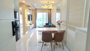 A modern kitchen with a dining area, a TV mounted on the wall, and a large window. - Terra Royal - Luxury Apartment & Hotel in Ho Chi Minh City (Thành phố Hồ Chí Minh)