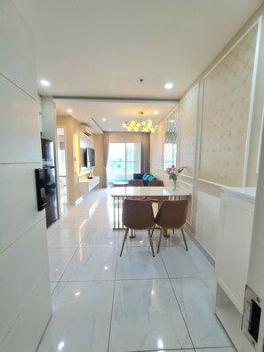 A modern kitchen with a dining area, a TV mounted on the wall, and a large window. - Terra Royal - Luxury Apartment & Hotel in Ho Chi Minh City (Thành phố Hồ Chí Minh)