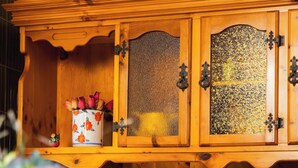 Ein Holzschrank mit Glastüren, eine Vase mit Blumen und ein Blumenkorb.