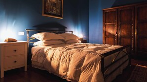 Ein Schlafzimmer mit Bett, Nachttisch, Schminktisch und einem gerahmten Bild an der Wand.