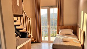 Een slaapkamer met een bed, een houten hoofdbord, gordijnen en uitzicht door een glazen deur.