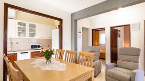 A dining area with a wooden table, chairs, a vase with flowers, and a kitchen in the background. - Holiday Home Franciska by Villas Guide (Blato)