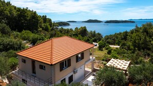 A two-story building with a tiled roof, surrounded by trees and overlooking a body of water. - Holiday Home Franciska by Villas Guide (Blato)