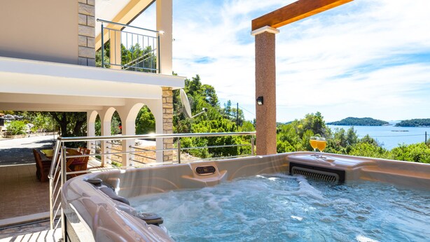A hot tub with a view of the sea, a balcony with outdoor seating, and a stone building. - Holiday Home Franciska by Villas Guide (Blato)