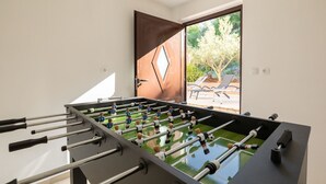A foosball table in a room with a door leading to an outdoor area with a pool and lounge chairs. - Holiday Home Franciska by Villas Guide (Blato)