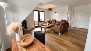 Ein modernes Wohnzimmer mit einem Holzesstisch, einer Couch, einem Fernseher und einer Lampe.