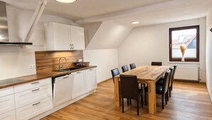 Eine moderne Küche mit weißen Schränken, einer Holzarbeitsplatte und einem Essbereich mit einem Holztisch und Stühlen.