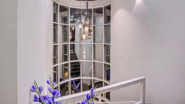 Een modern interieur met een gebogen trap, een glazen omlijsting en een kroonluchter.