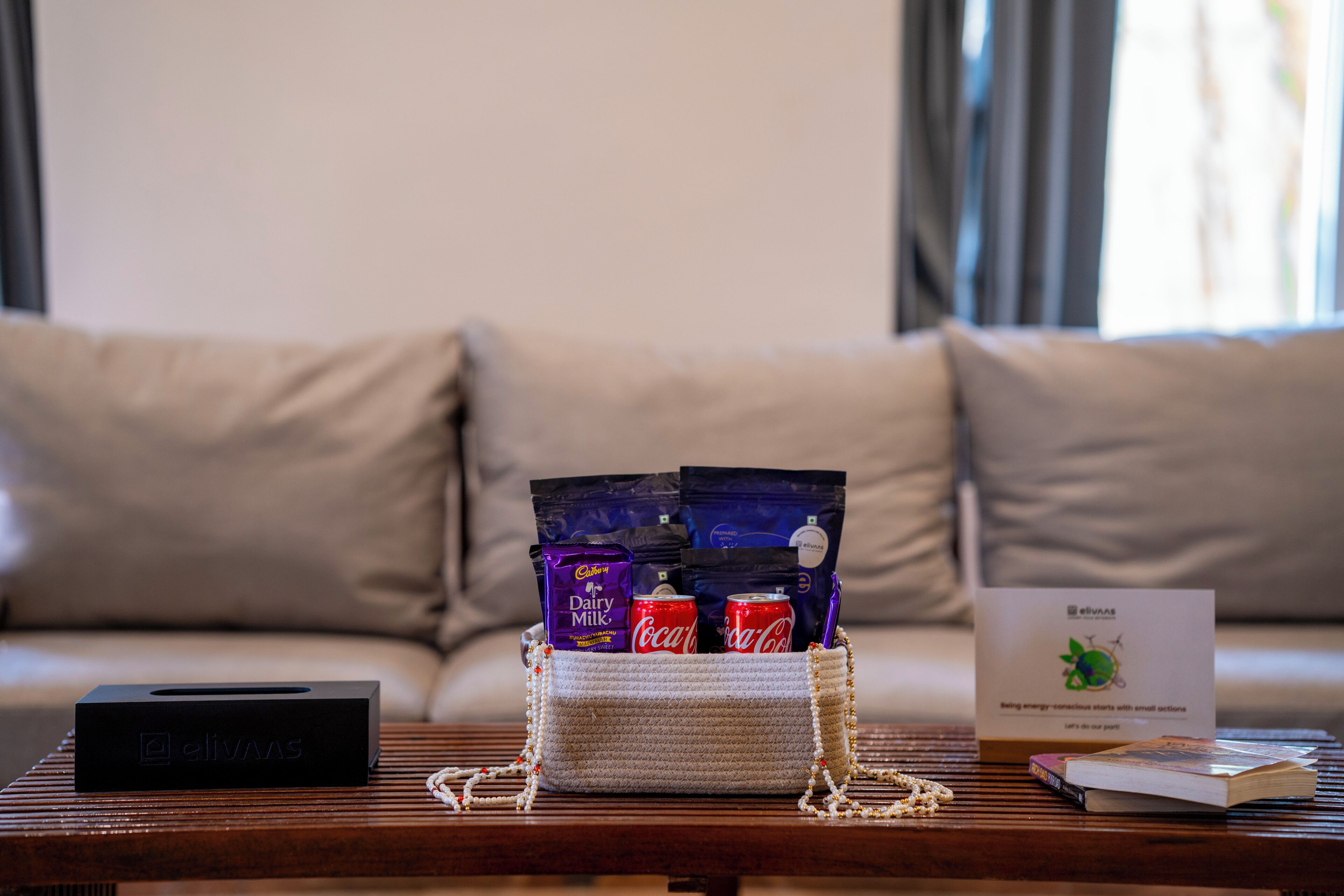 A sofa, a coffee table with a box, a bag, and some items on it.
