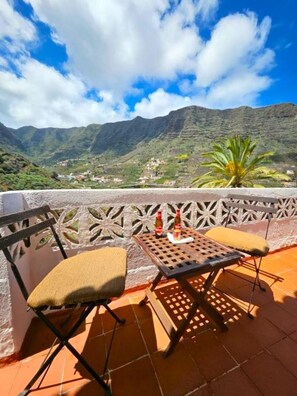 Una terraza con dos sillas y una mesa, con vistas a un paisaje montañoso.