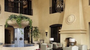 Eine Lobby mit einer zentralen Springbrunnen, Sitzbereichen und einer Wandverkleidung.