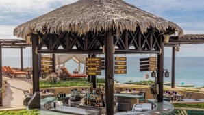 Ein Resort mit Barbereich, einem Pool mit Mosaikgestaltung und einer strohgedeckten Struktur.