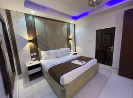 Una habitación de hotel moderna con una cama grande, dos mesitas de noche y cabecera integrada.