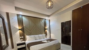 A modern bedroom with a large bed, bedside tables, a wardrobe, and a decorative wall panel. - Presken Hotel Signature (Lagos)