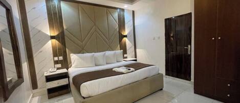 A modern bedroom with a large bed, bedside tables, a wardrobe, and a decorative wall panel.