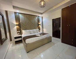Un dormitorio moderno con una cama grande, mesitas de noche, un armario y un panel decorativo en la pared.