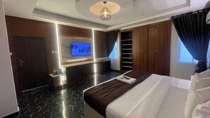 A modern hotel room with a large bed, a flat-screen TV mounted on the wall, a built-in wardrobe, and a ceiling light fixture. - Presken Hotel Signature (Lagos)
