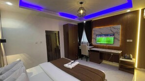 A hotel room with a bed, desk, TV, and a view of the city. - Presken Hotel Signature (Lagos)