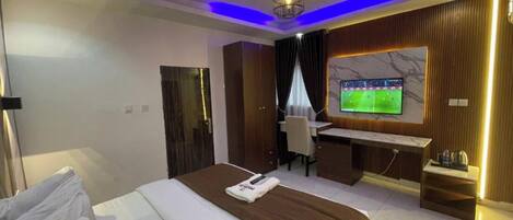 Habitación de hotel con cama, escritorio, televisión y vistas a la ciudad.