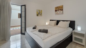 Camera da letto con un letto, un comodino, un quadro e una porta che dà su uno spazio all'aperto.
