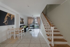 Un amplio salón con una escalera, una mesa de comedor y un sofá.