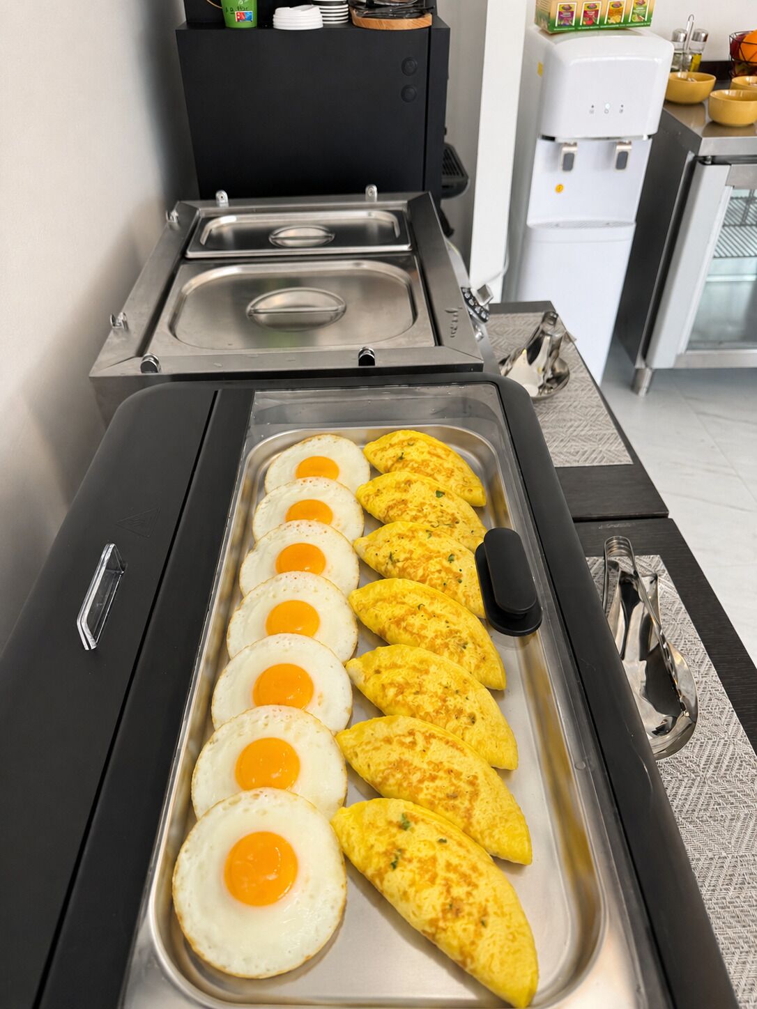 A kitchen with a stainless steel tray containing eggs and omelettes.