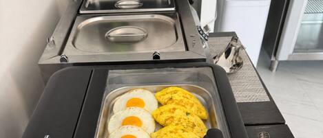 A kitchen with a stainless steel tray containing eggs and omelettes.