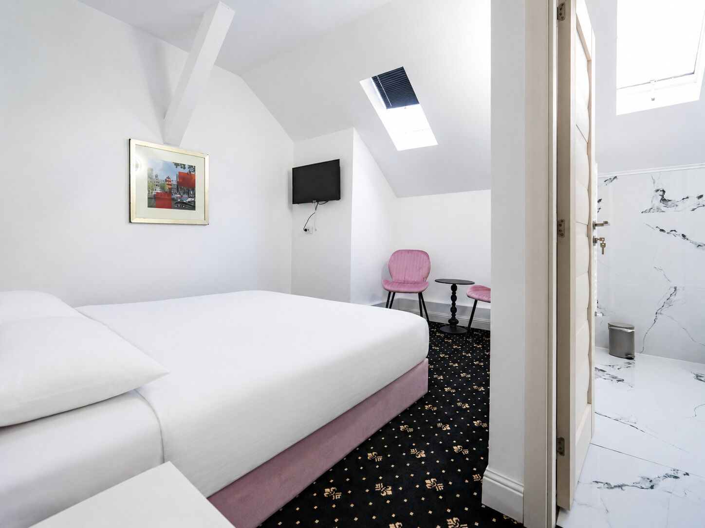 Ein Hotelzimmer mit Bett, Schreibtisch, Stuhl, Fernseher und einem Bild an der Wand.