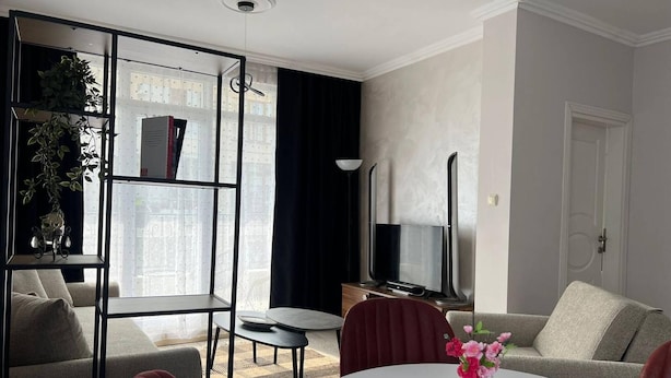 A modern living room with a sofa, a coffee table, a TV, and a bookshelf. - Room-sunny Beach Central Apartment - 4 G (Nessebar)