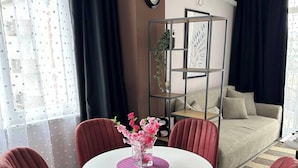 A modern living room with a round table, four red chairs, a white air conditioning unit, a bookshelf, and a sofa. - Room-sunny Beach Central Apartment - 4 G (Nessebar)