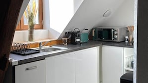 A modern kitchen with white cabinets, a black countertop, and a window providing natural light. - L'escale Troyenne (T31) (Troyes)