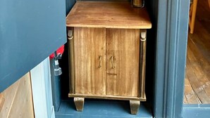 A wooden cabinet with two drawers and a shelf, a framed abstract artwork above it, and a vase with dried plants on the right. - L'escale Troyenne (T31) (Troyes)