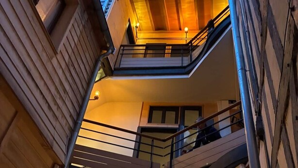 A multi-level building with balconies, staircases, and a warm interior lighting. - L'escale Troyenne (T31) (Troyes)