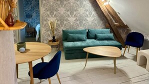 A cozy loft bedroom with a green sofa, two chairs, a small table, and a decorative vase. - L'escale Troyenne (T31) (Troyes)