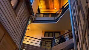 Un edificio de varios niveles con balcones, escaleras e iluminación cálida en su interior.